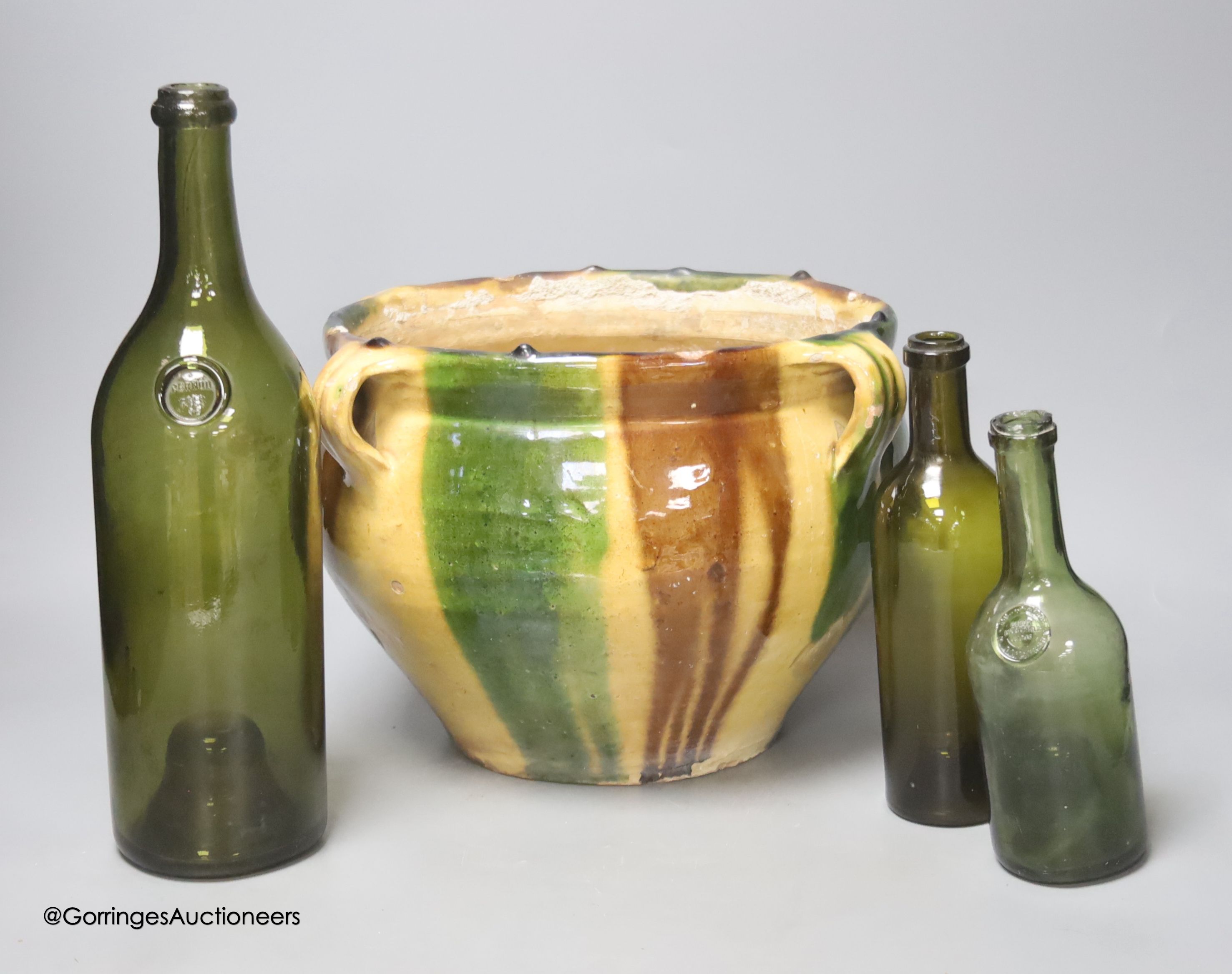 A French tin glazed pottery jardiniere and three French green glass bottles, tallest 31cm